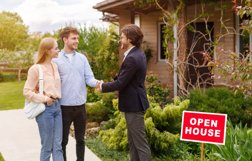 New home owners shaking hands with their real estate agent near residential building outside, copy space